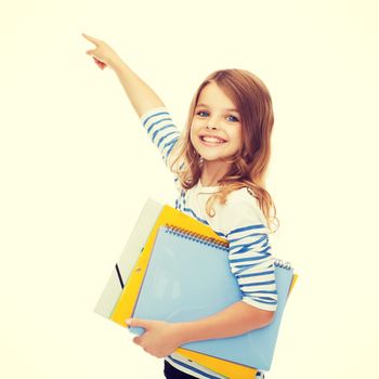 education, school and virtual screen concept - cute little girl with colorful folders pointing in the air or virtual screen