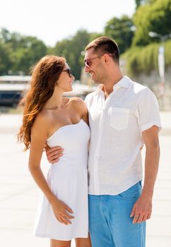 love, travel, tourism, people and friendship concept - smiling couple wearing sunglasses hugging in city