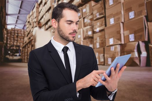 Cheerful businessman touching digital tablet against worker with fork pallet truck stacker in warehouse