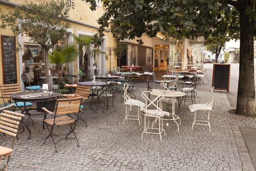 An outside cafe on a pavement with a lot of chairs and tables