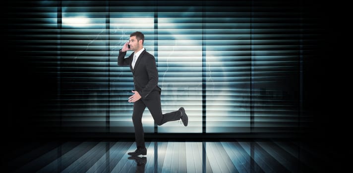 Businessman running on the phone  against room with large window looking on city