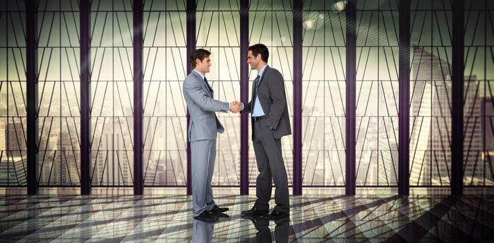 Businessmen shaking hands against room with large window looking on city