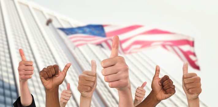 Hands showing thumbs up against american flag and skyscraper
