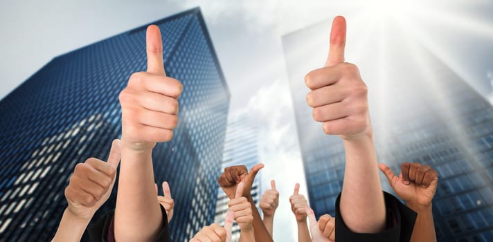 Hands showing thumbs up against low angle view of skyscrapers