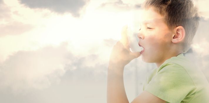 Boy using an asthma inhaler in clinic against grey cloudy sky