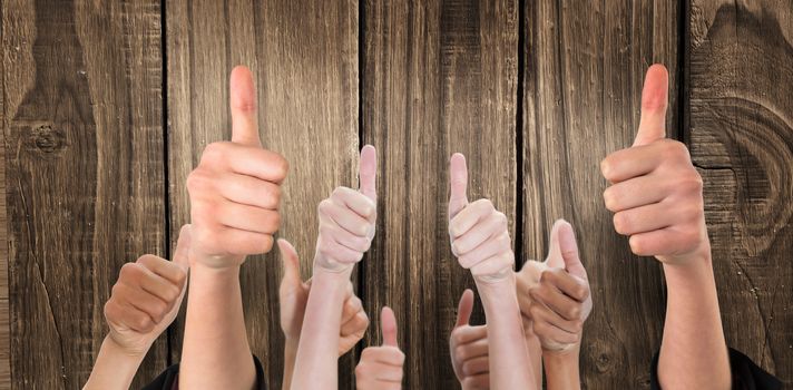 Hands showing thumbs up against wooden background