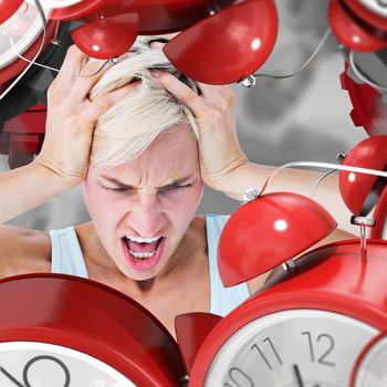 Angry blonde woman screaming and holding her head  against grey vignette