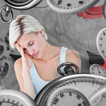 Depressed blonde woman with hand on temple  against grey background