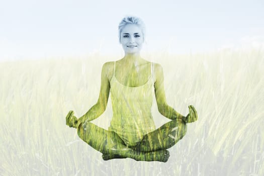 Toned young woman sitting in lotus pose against green meadow