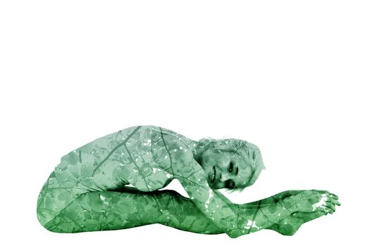 Toned woman doing the paschimottanasana pose against branches and leaves
