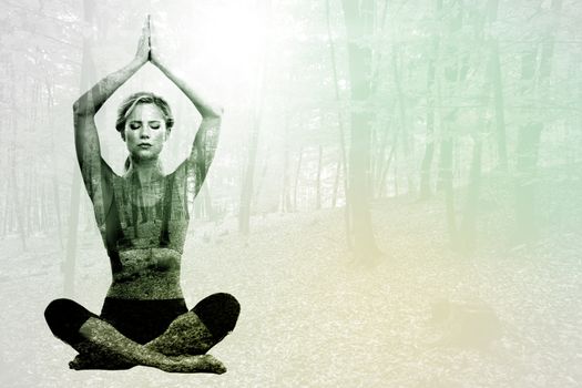 Calm blonde meditating in lotus pose with arms raised against autumnal forest