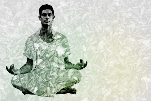 Handsome man in white meditating in lotus pose against detail shot of dry leaves
