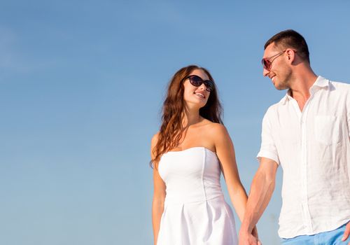 concept - smiling couple wearing sunglasses walking outdoors