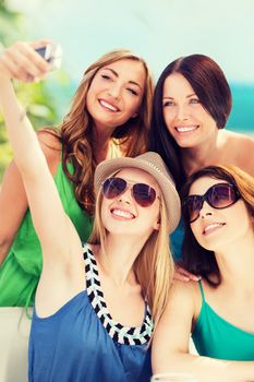 summer holidays and technology - girls taking photo in cafe on the beach