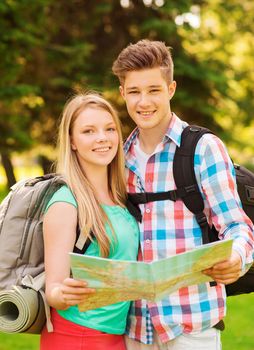 travel, vacation, tourism and friendship concept - smiling couple with map and backpack in forest