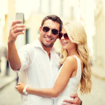 summer holidays, technology, love, relationship and dating concept - smiling couple taking selfie with smartphone in the city