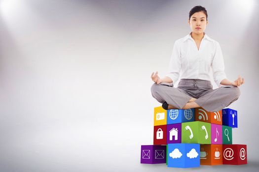 Businesswoman sitting in lotus pose against grey background