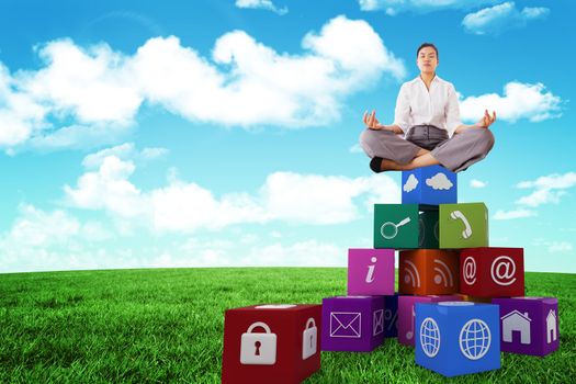 Businesswoman sitting in lotus pose against blue sky over green field