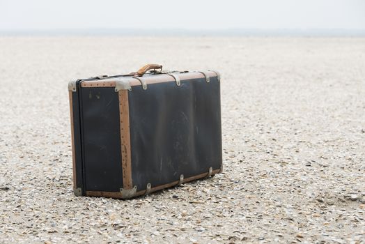 old vintage used leather suitcase for traveling on the sandy beach