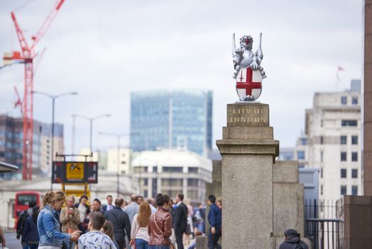 LONDON, UK - JUNE 23: Busy pavement on London Bridge, with City of London dragon in the foreground. June 23, 2015 in London.