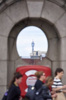 LONDON, UK - JUNE 23: The BT Tower framed in architectural detail, in the far background, with people passing by in the blurred foreground. June 23, 2015 in London.