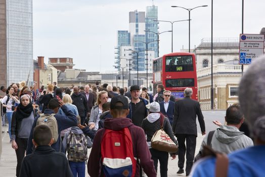 LONDON, UK - JUNE 23: Busy pavement on London Bridge, with red Routemaster bus in the background. June 23, 2015 in London.