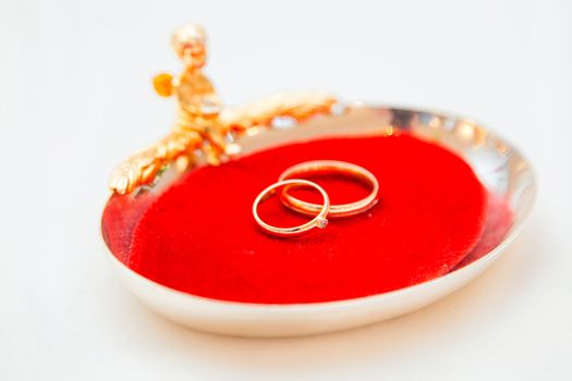 Two wedding rings on a red base with an angel.