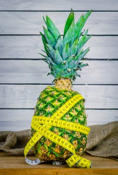 Pineapple fruit with measure tape on a wooden table