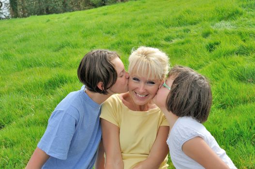 A mother smiles as she receives a kiss on the cheek from her young daughters