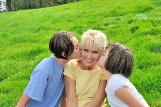 A mother smiles as she receives a kiss on the cheek from her young daughters