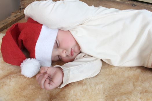 Sleeping christmas baby on a sheep skin rug wearing 