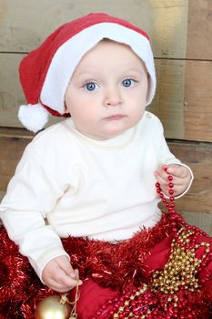 Baby boy wearing a christmas hat playing with decorations