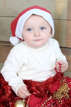 Baby boy wearing a christmas hat playing with decorations
