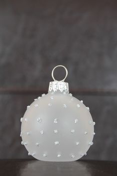 Glass christmas ball against leather and dark wood background