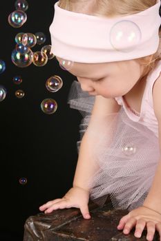 Blond girl wearing a ballet tutu playing with bubbles