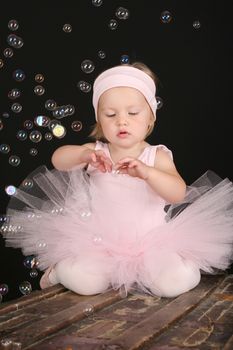 Blond girl wearing a ballet tutu playing with bubbles