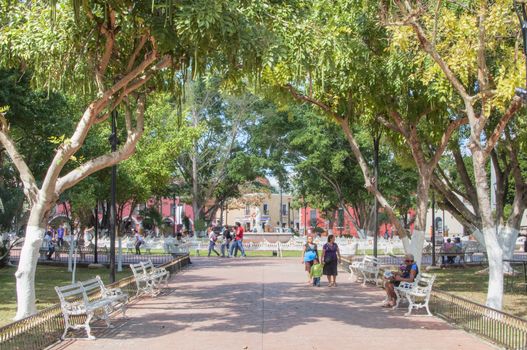 VALLADOLID, MEXICO - JANUARY 20, 2015: Locals and tourists enjoy beautiful warm winter weather in the shady park surrounding the fountain in the town square of Valladolid, Mexico