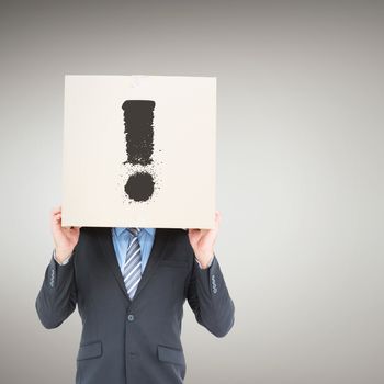 Businessman hiding head with a box against grey vignette