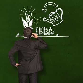 Thinking businessman scratching head against green