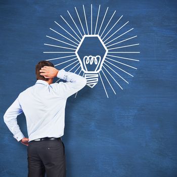Thinking businessman scratching head against blue chalkboard