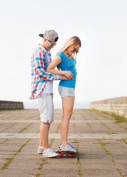 holidays, vacation, love and friendship concept - smiling couple with skateboard outdoors