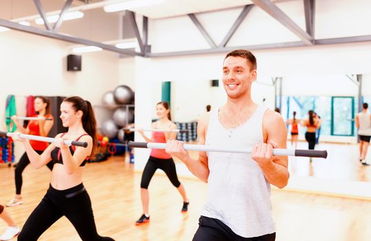 fitness, sport, training, gym and lifestyle concept - group of smiling people working out with barbells in the gym