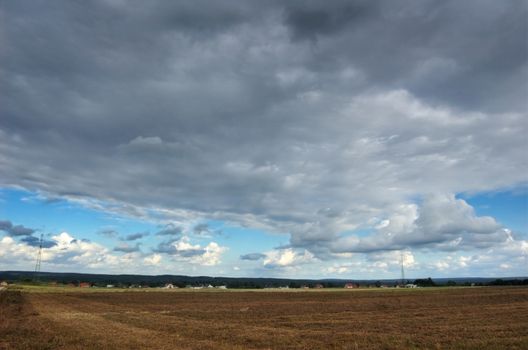 Rural landscape. Storm over the field and small village.