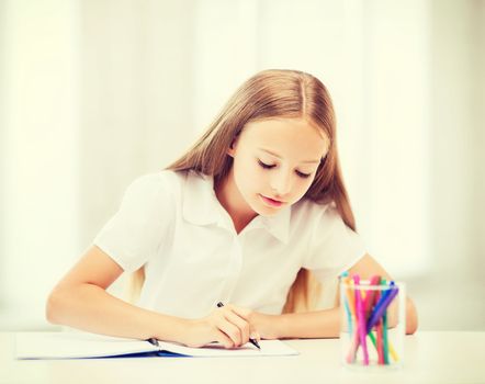 education and school concept - little student girl drawing at school