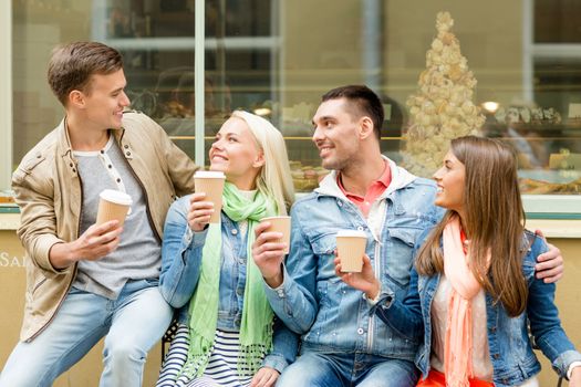 friendship, travel, drink and vacation concept - group of smiling friends with take away coffee