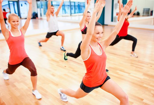 fitness, sport, training, gym and lifestyle concept - group of smiling people stretching in the gym