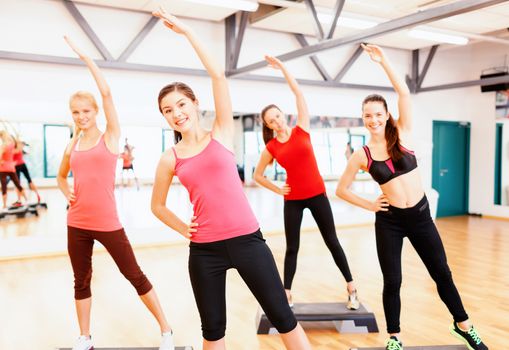 fitness, sport, training, gym and lifestyle concept - group of smiling female doing stretching in gym