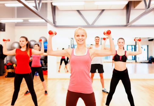 fitness, sport, training, gym and lifestyle concept - group of smiling people working out with dumbbells in the gym