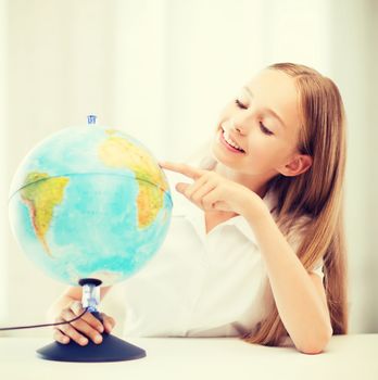 education and school concept - little student girl with globe at school