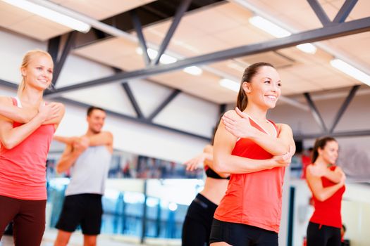 fitness, sport, training, gym and lifestyle concept - group of smiling people stretching in the gym